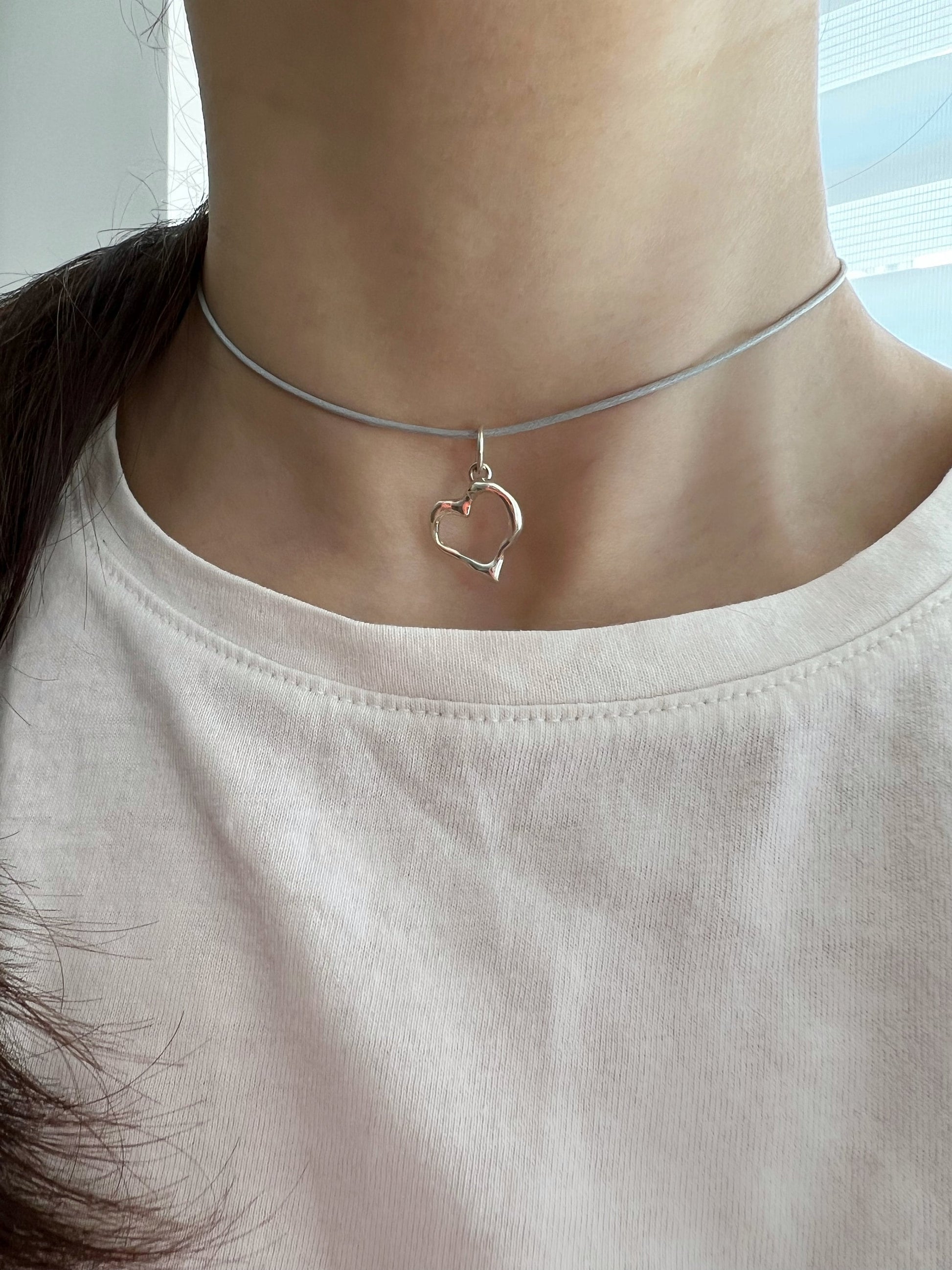 Sterling silver heart and flower charms on pastel cords flat lay