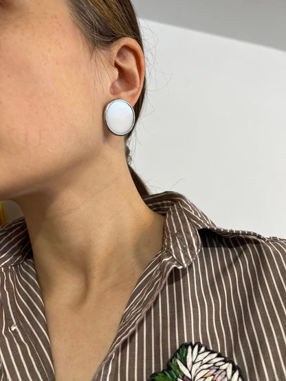 White enamel round stud earrings close up on ear