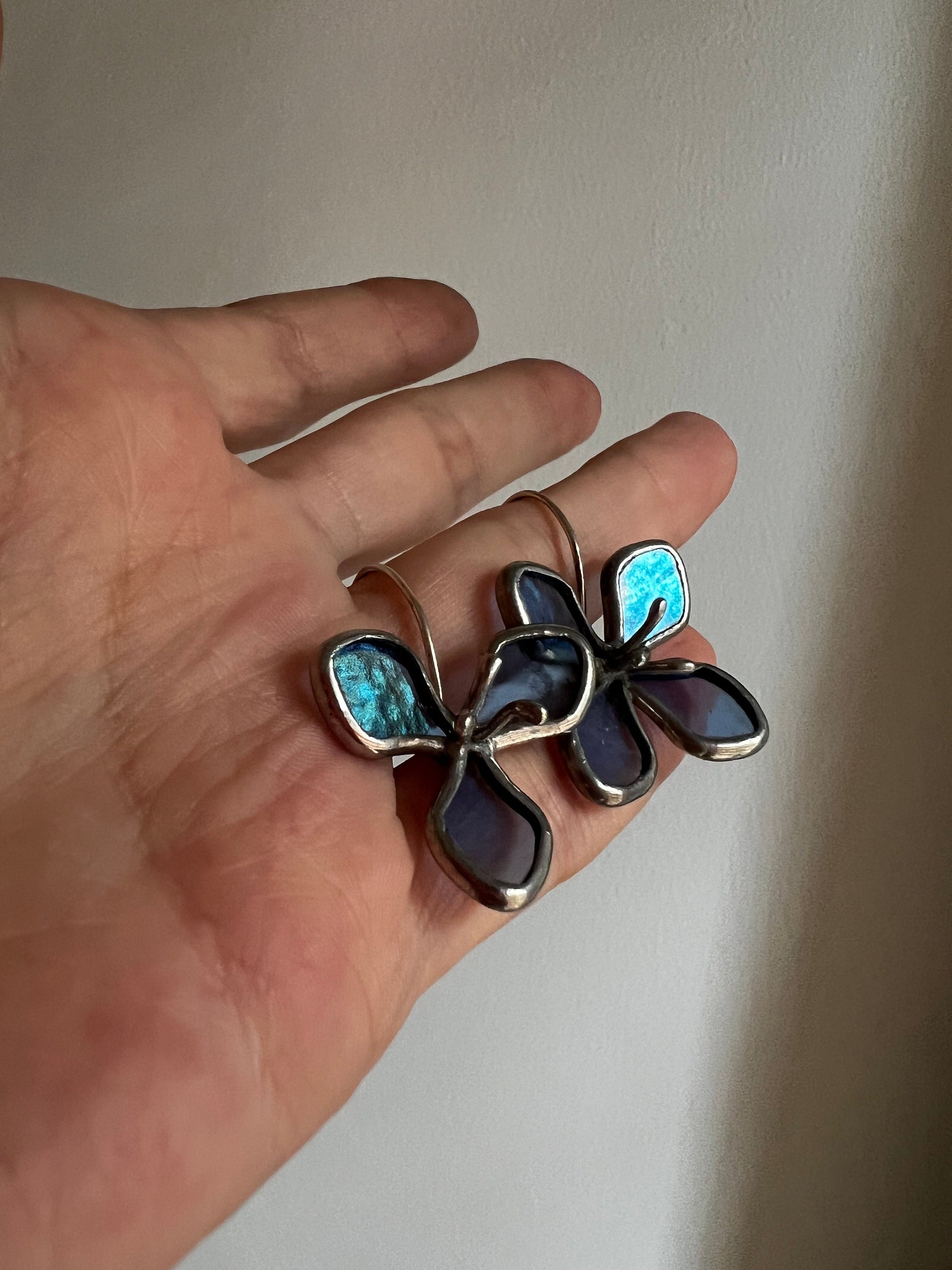 Dark aquamarine floral stained glass earrings in hand