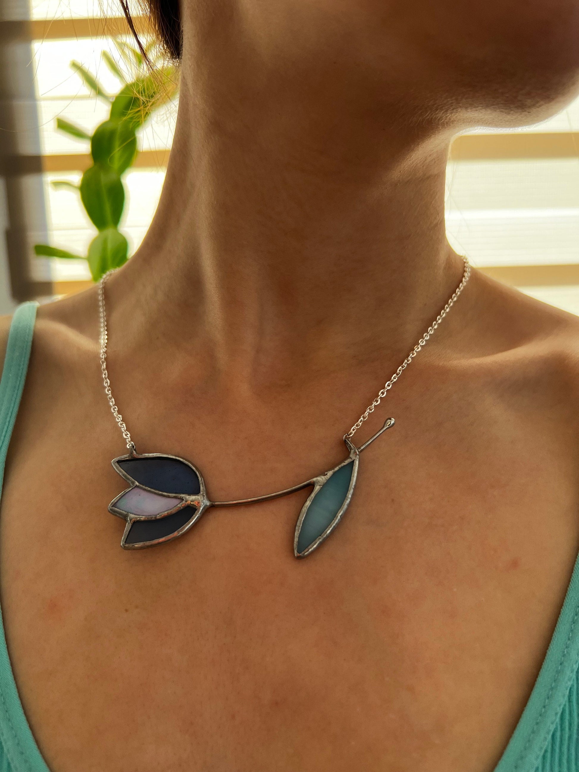 Stained glass necklace with deep blue tulip and pale blue leaf. Handmade floral pendant on silver chain, botanical style.