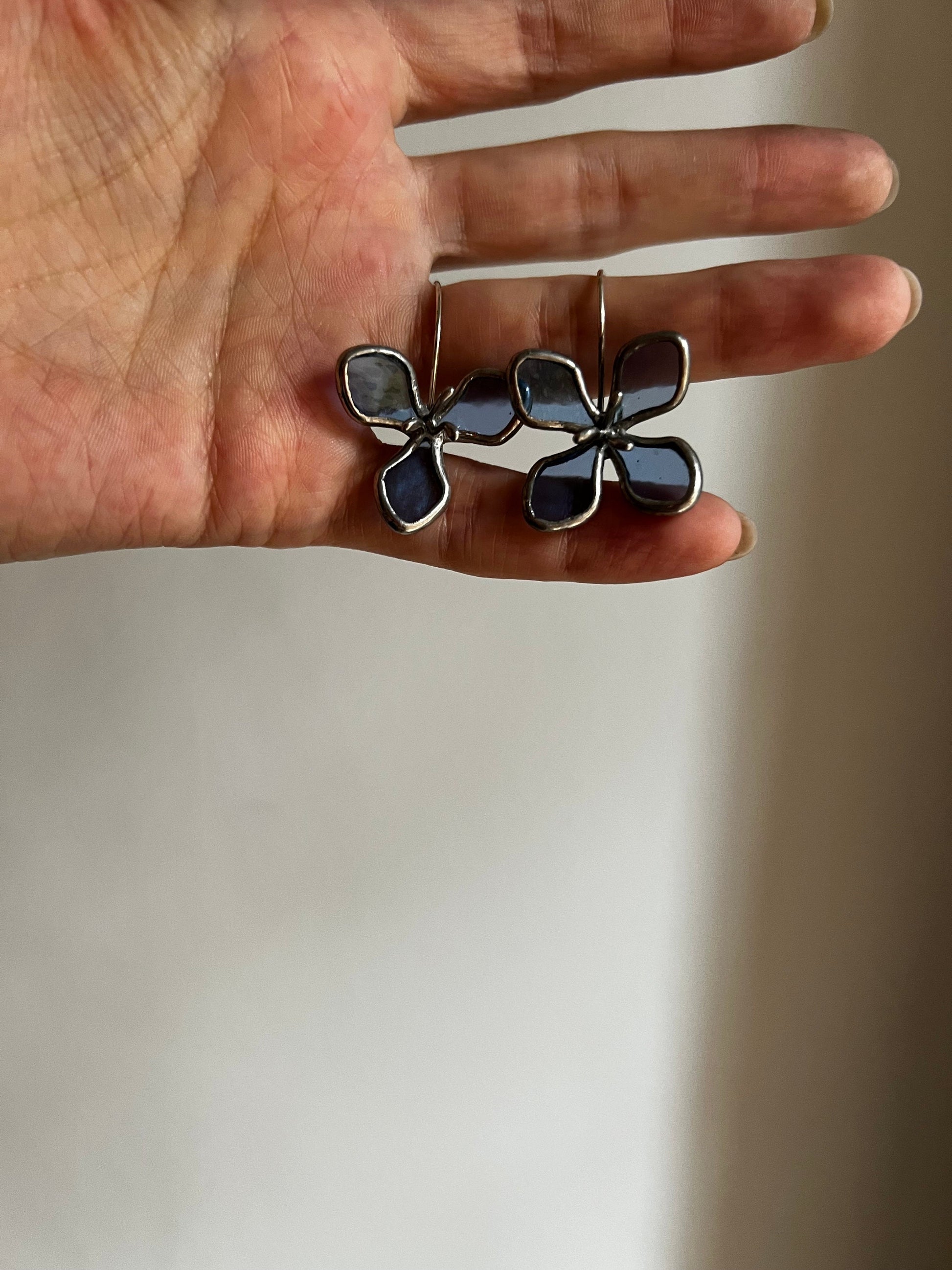 Pair of blue stained glass hydrangea earrings shown in hand