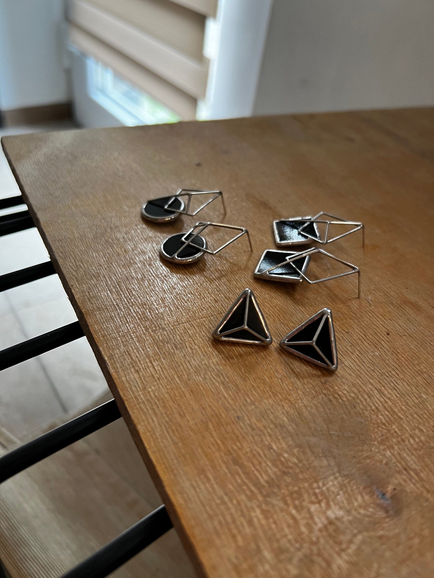 Set of black glass earrings and triangle studs on table