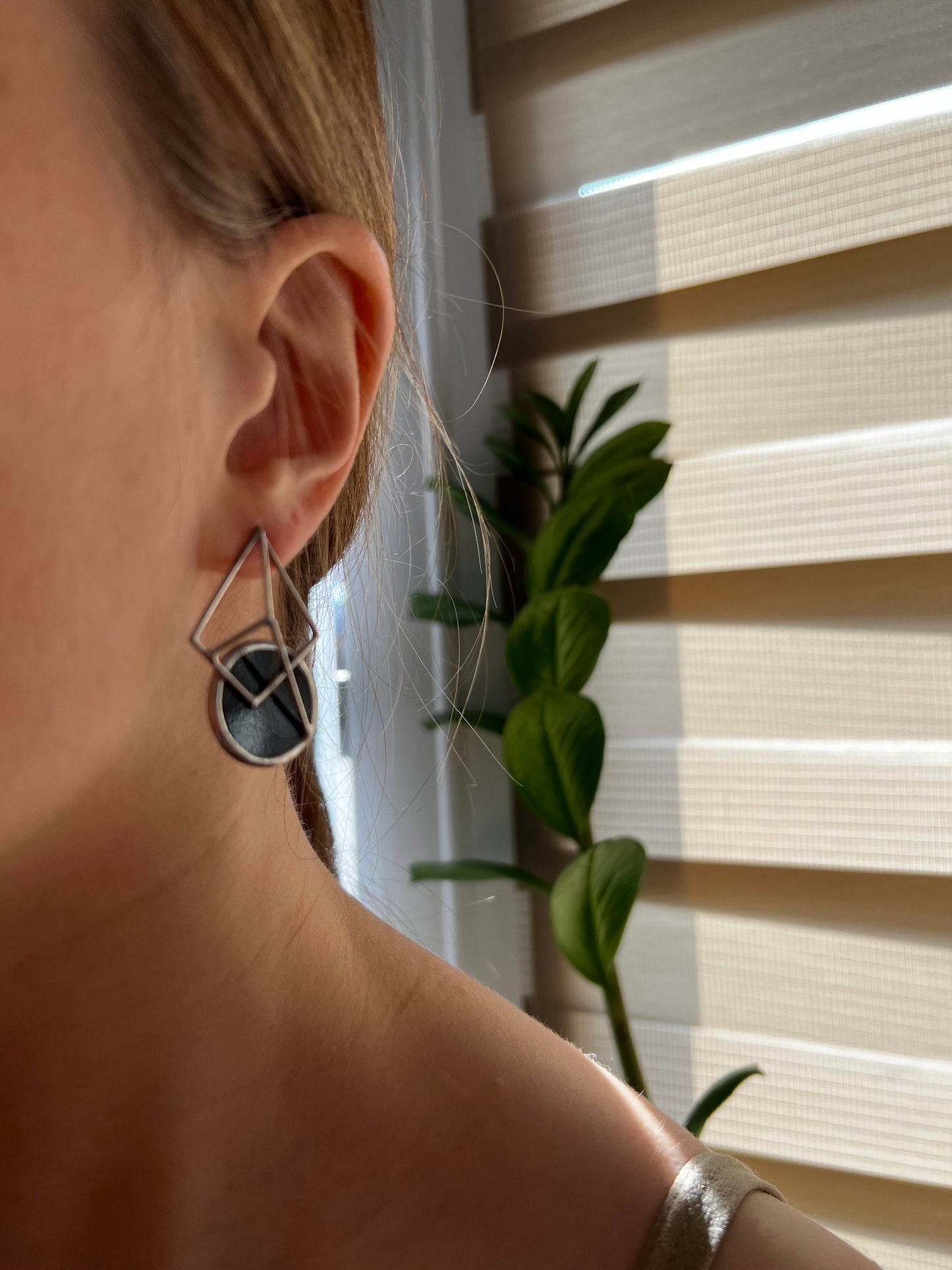 Side angle view of geometric black stained glass earrings on model