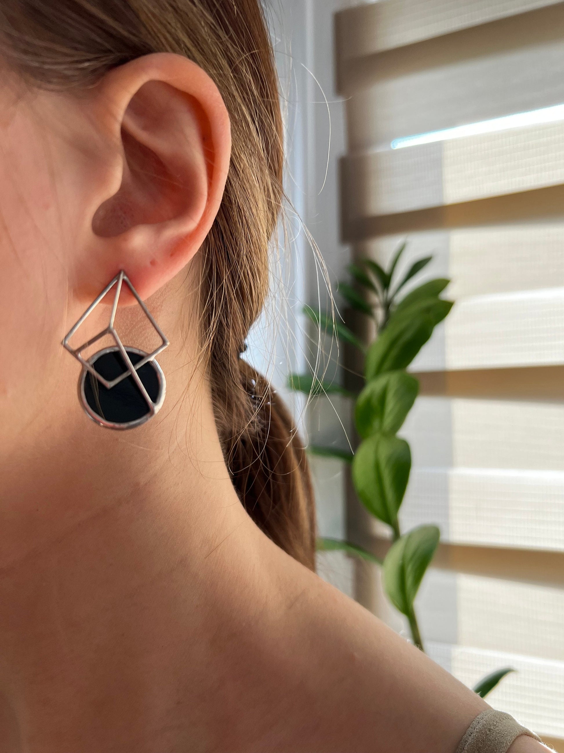 Black circular stained glass earrings worn with modern outfit