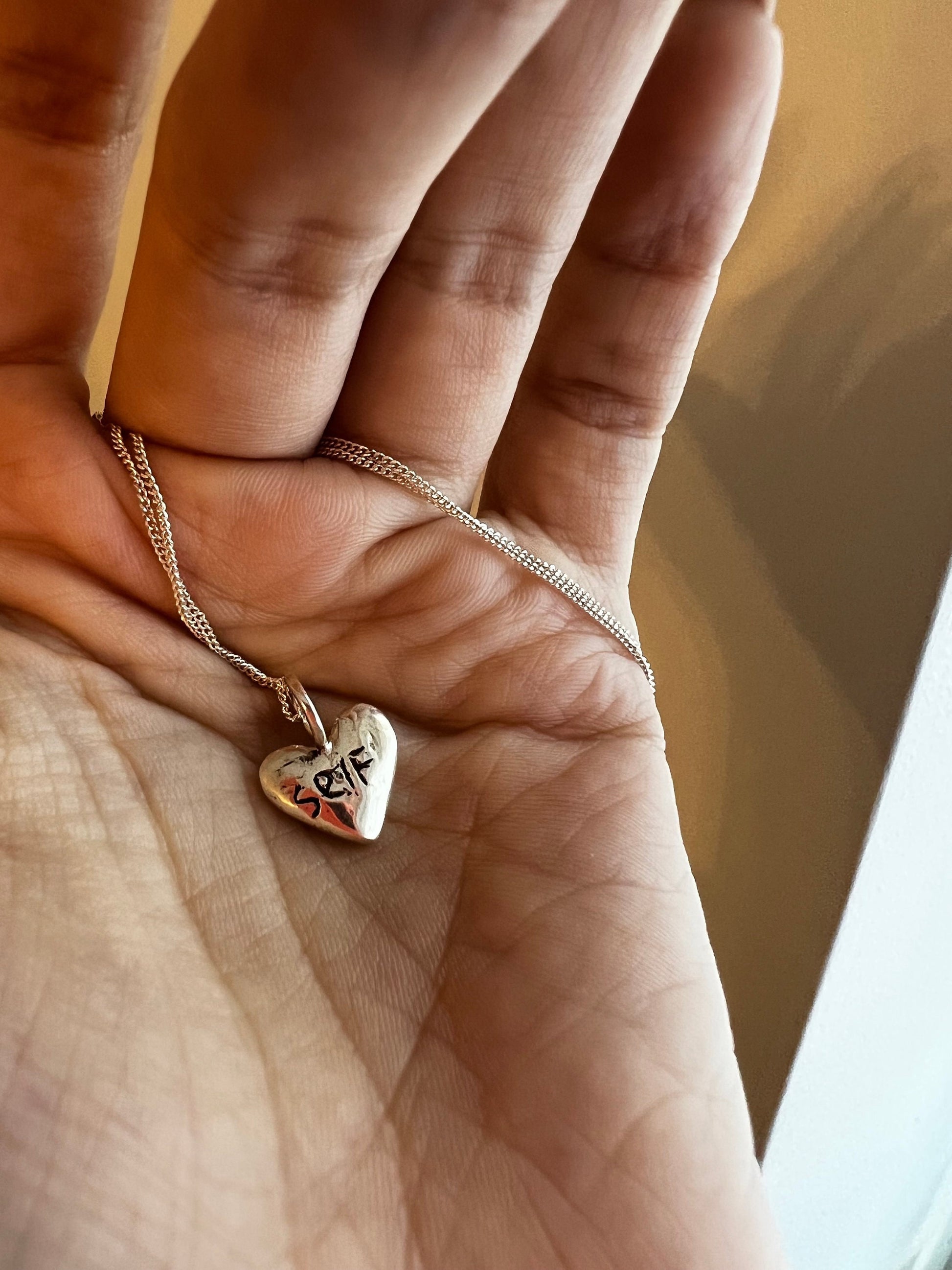 Personalized sterling silver puffy heart necklace on hand