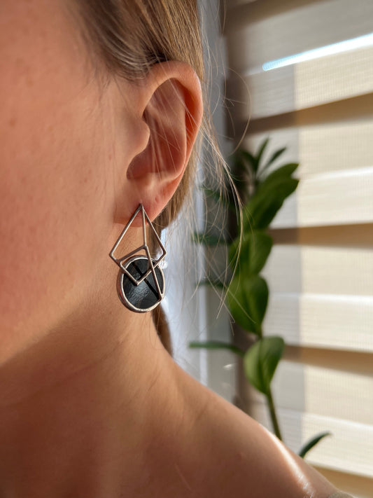 Hand holding black geometric stained glass stud earrings