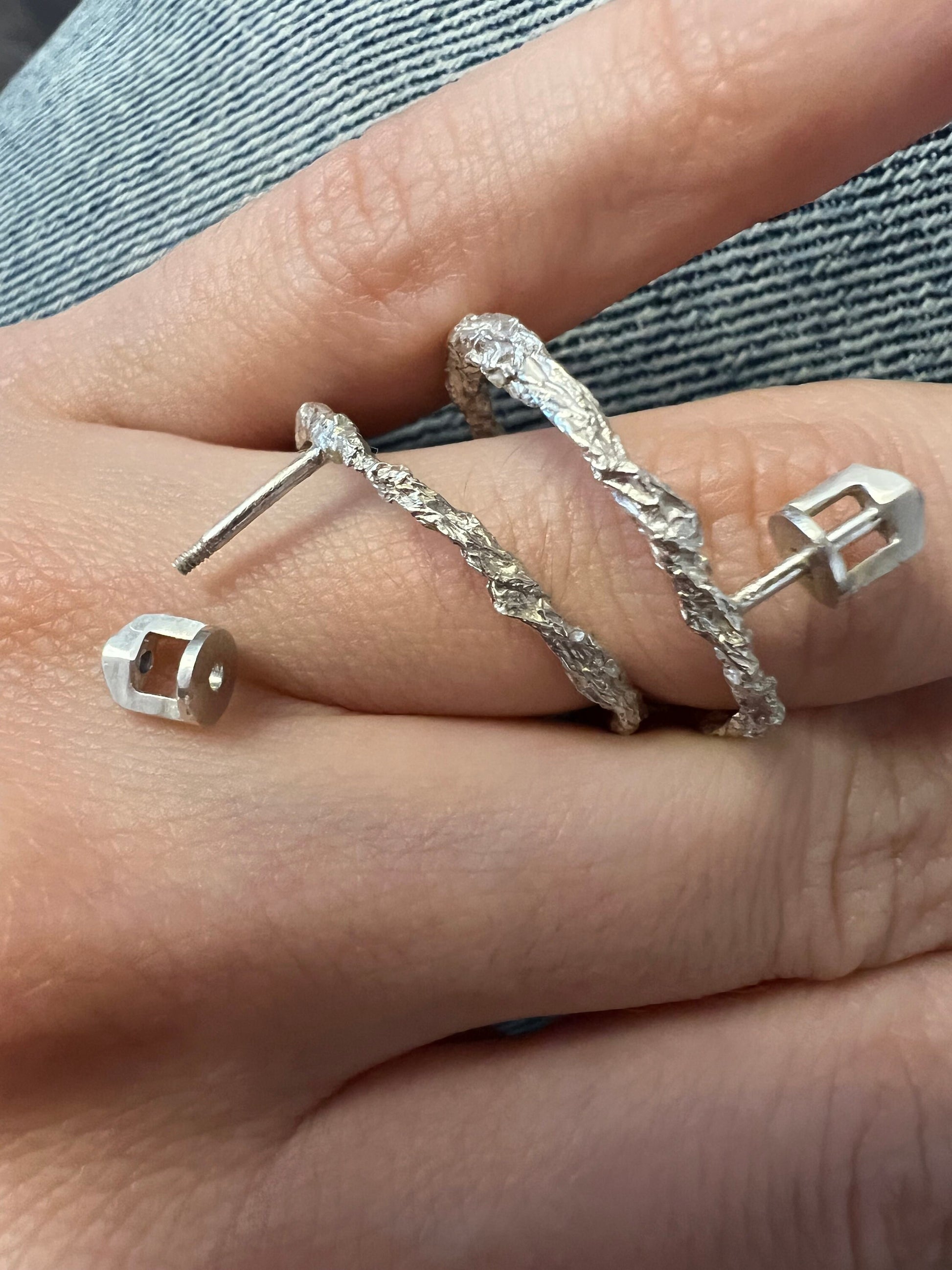 Hand wearing matching hammered silver jewelry set including textured circle studs.