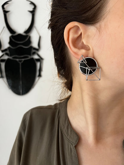 Black geometric earrings worn on ear side view minimalist gothic look