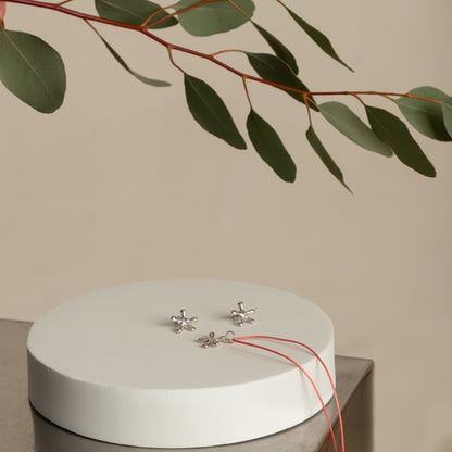 Silver flower pendant and earrings on display – minimalist handmade carm