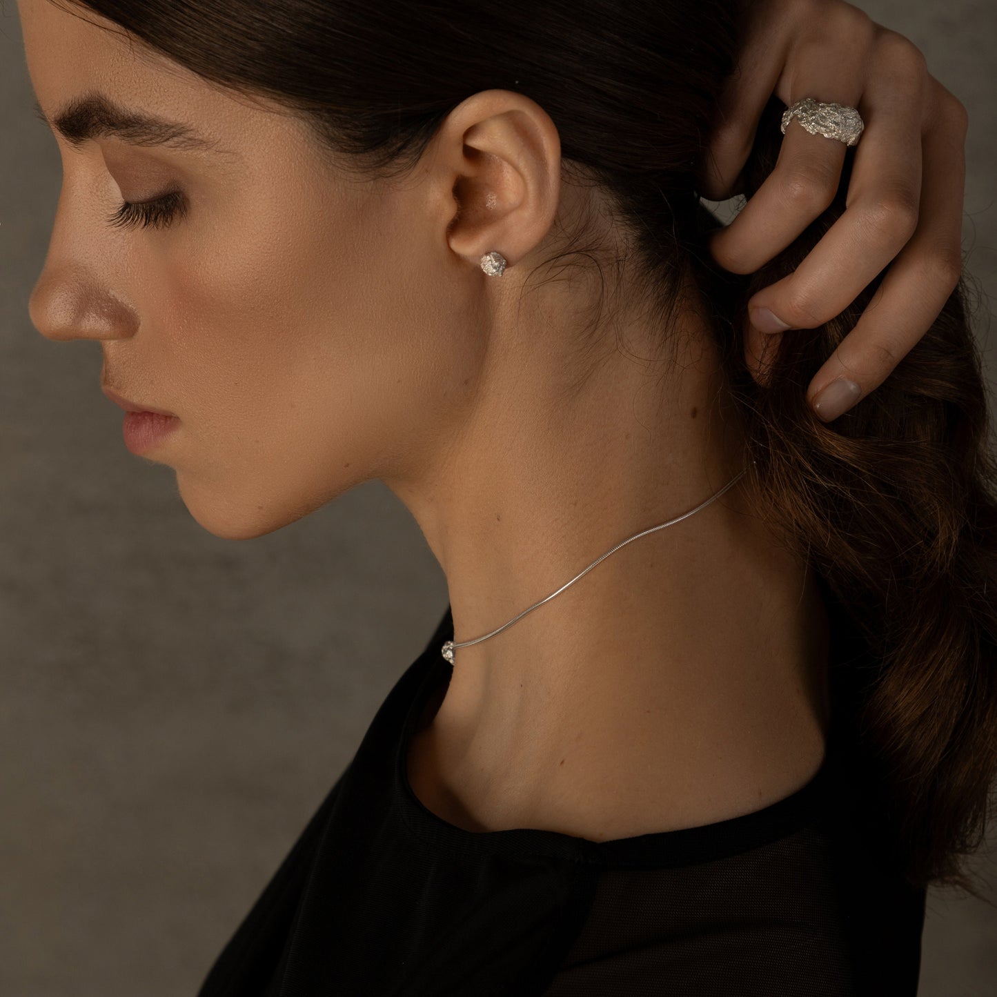 Side view of handmade crumpled silver ring on model