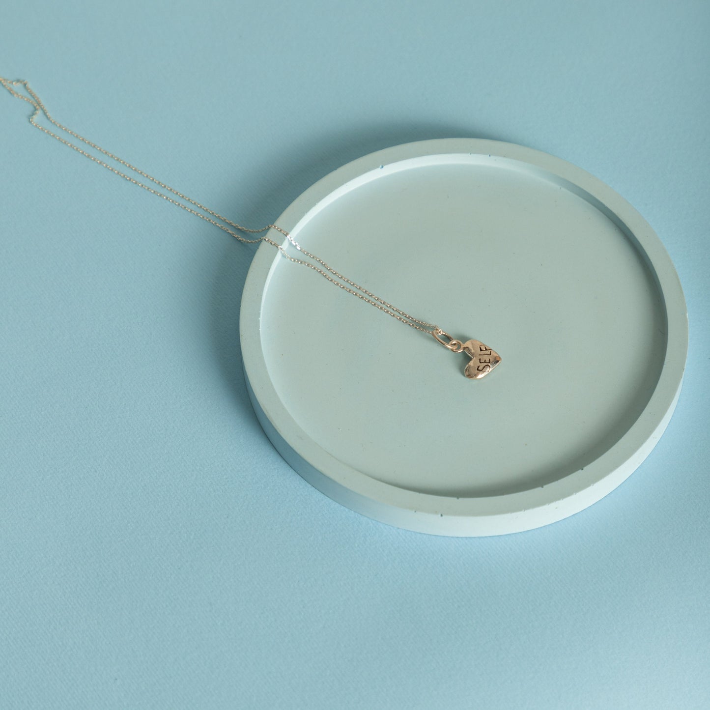 Puffy heart necklace styled on ceramic plate minimal aesthetic