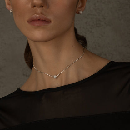 Model touching neck wearing small silver studs.