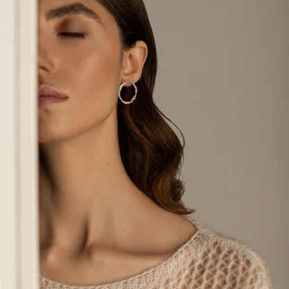 Model wearing sterling silver textured hoop studs with minimal makeup