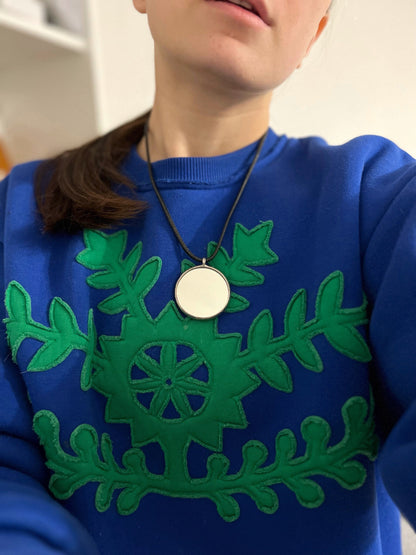 Model in blue sweater with mirror pendant