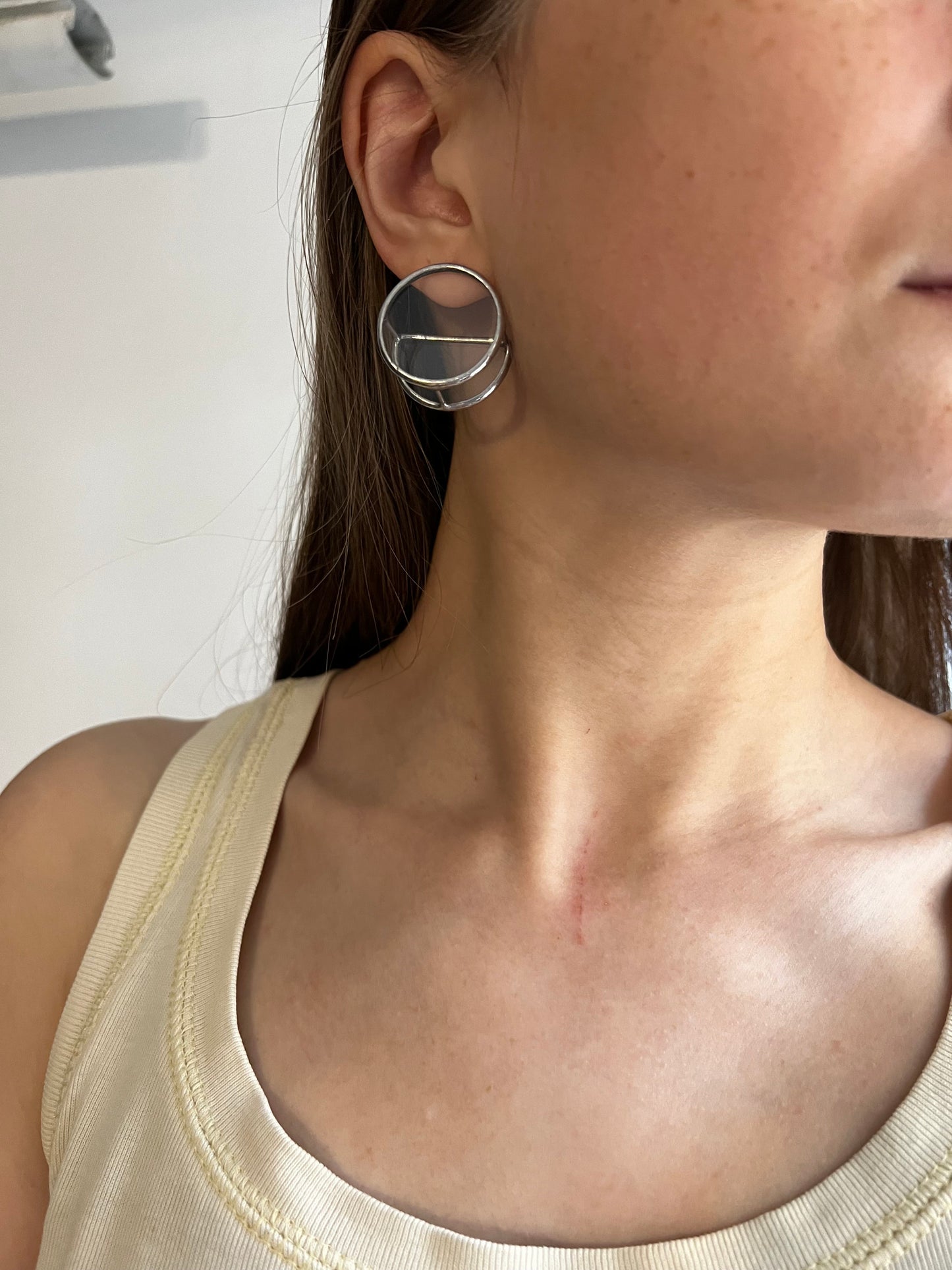 Woman wearing large geometric stained glass earrings with silver posts