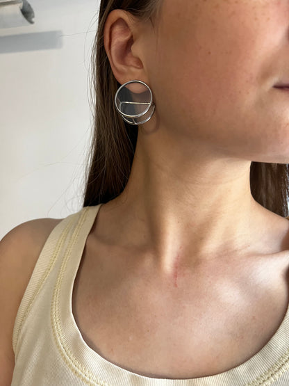 Woman wearing large geometric stained glass earrings with silver posts