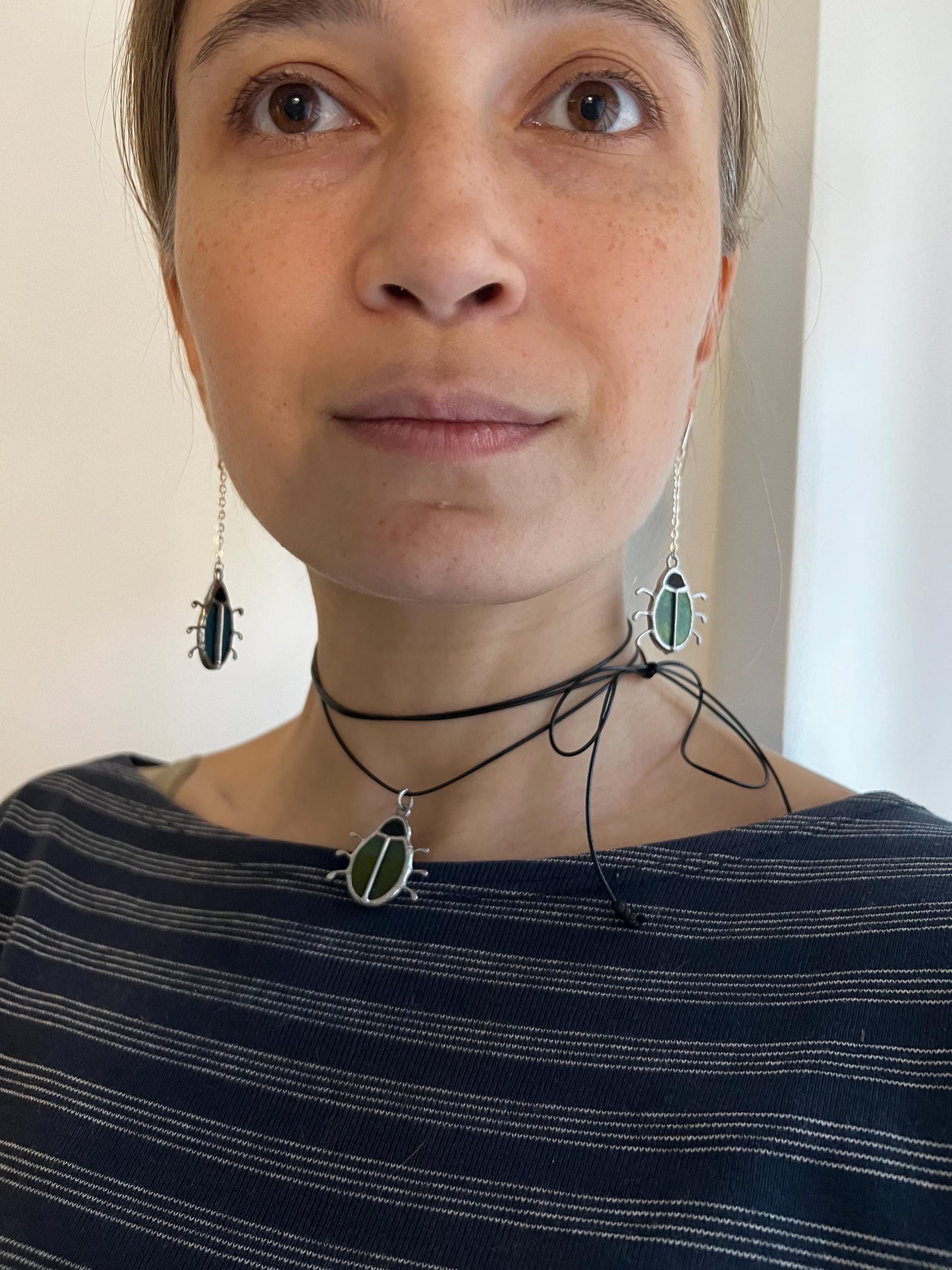 Model wearing stained glass bug necklace and earrings, nature jewelry set
