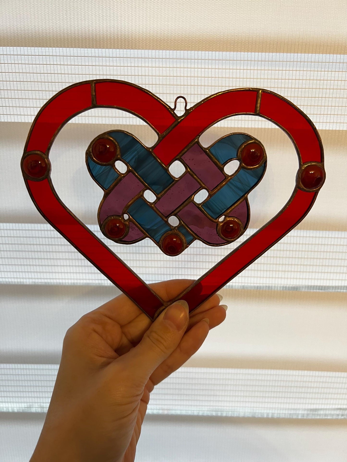 Red stained glass heart suncatcher hanging in window
