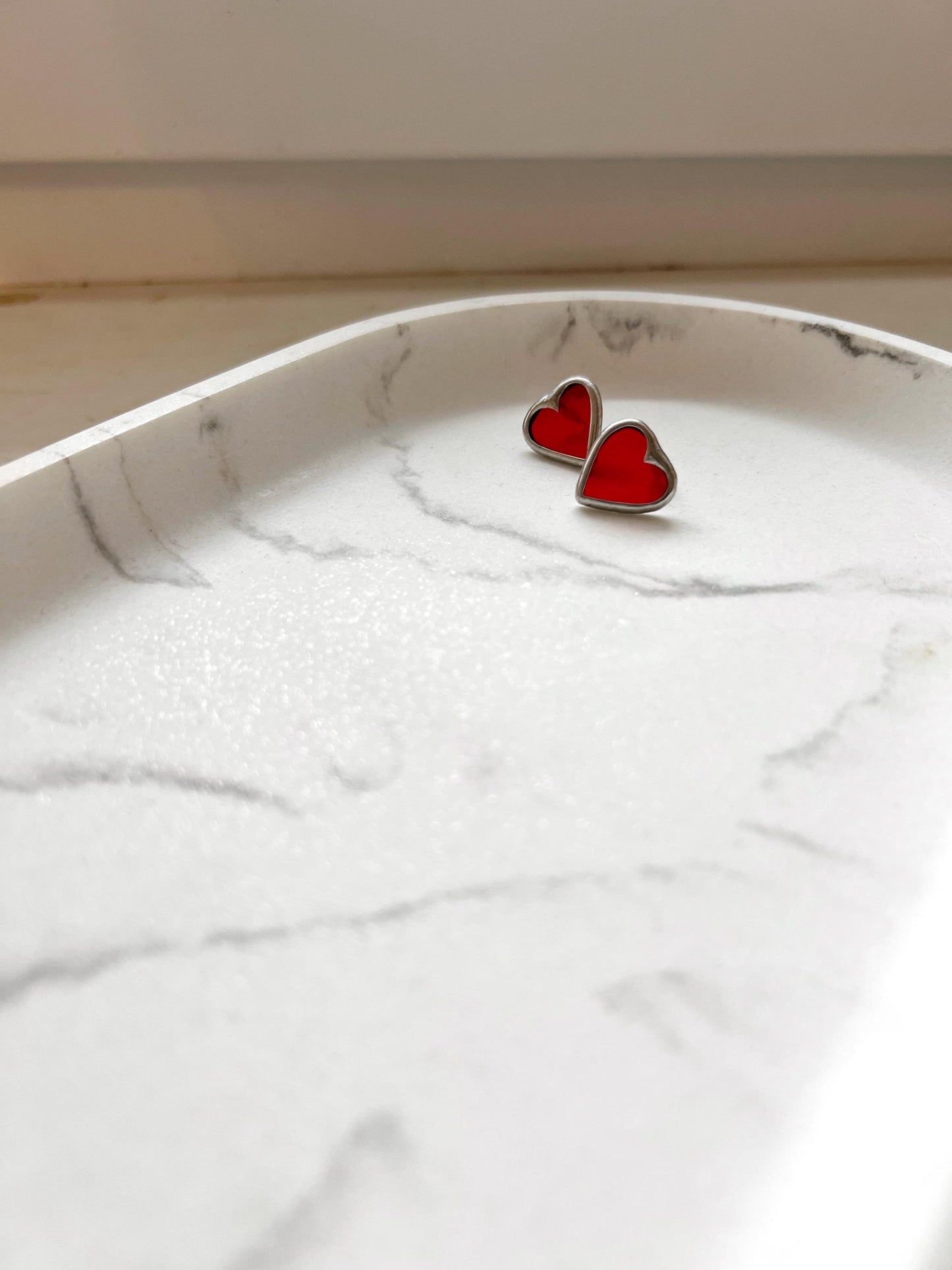 Deep red heart earrings in a silver frame on a white tray