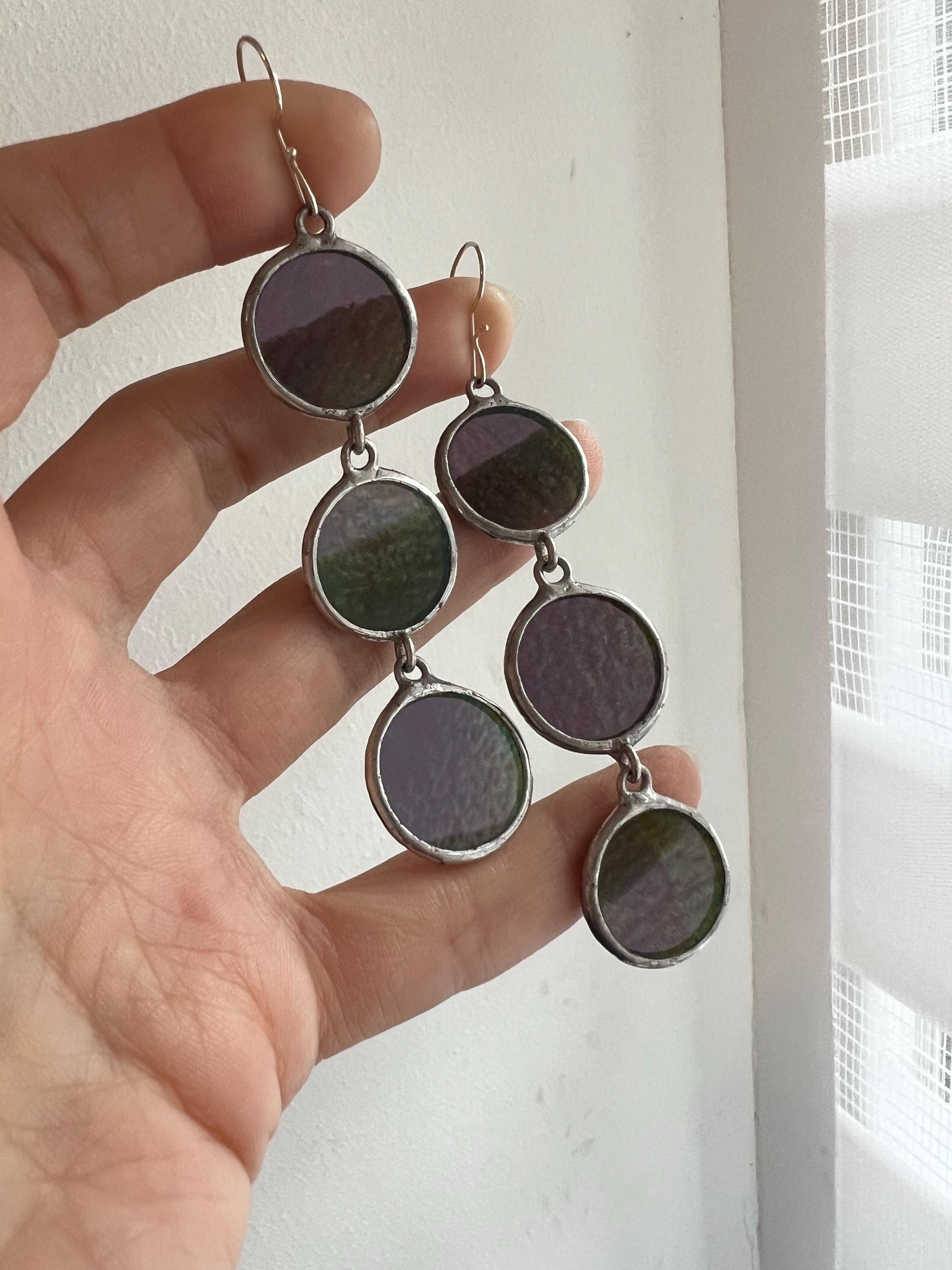 Handmade iridescent stained glass earrings shown in hand