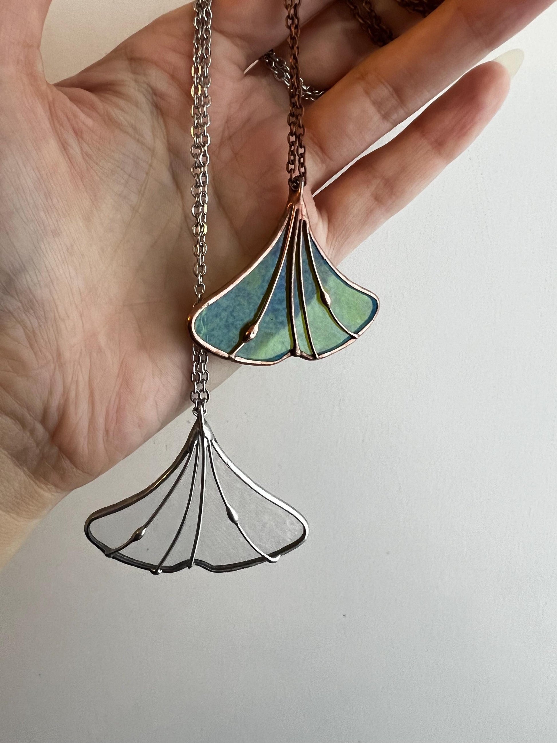 Hand holding green stained glass ginkgo leaf necklace