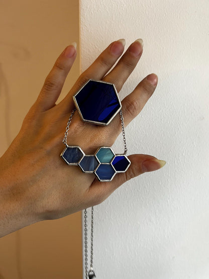 A blue geometric honeycomb ring combined with a necklace of blue stained glass elements - a modern jewelry set.