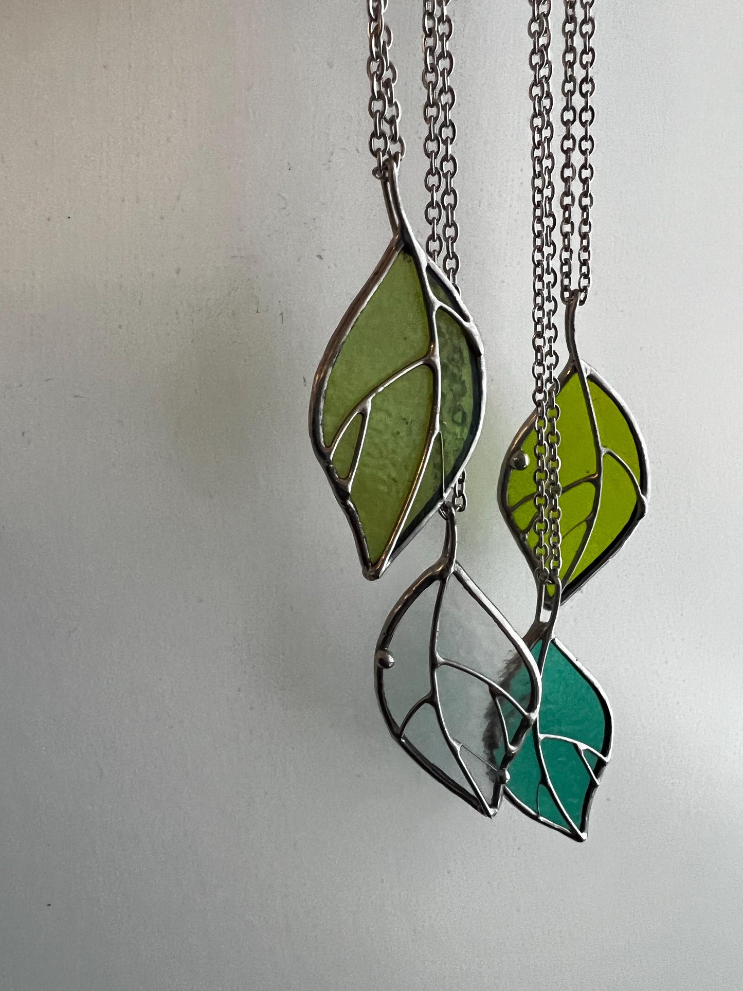 The leaf-shaped necklace hangs beautifully, showcasing different shades of green and clear glass.
