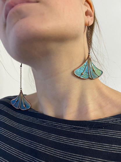 Model wearing iridescent blue-green ginkgo stained glass pendant
