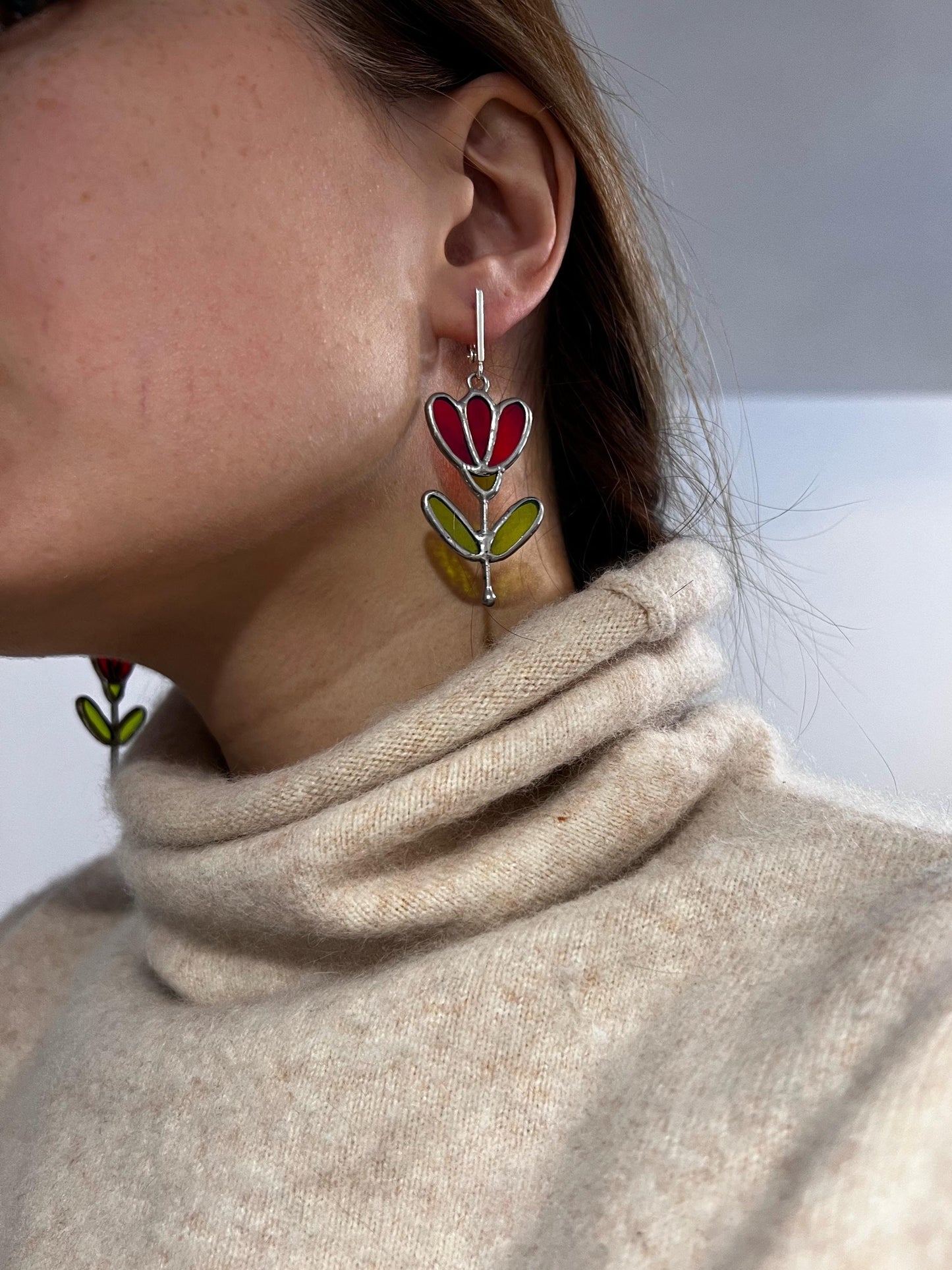 Red stained glass flower earrings worn on ear, botanical dangle jewelry