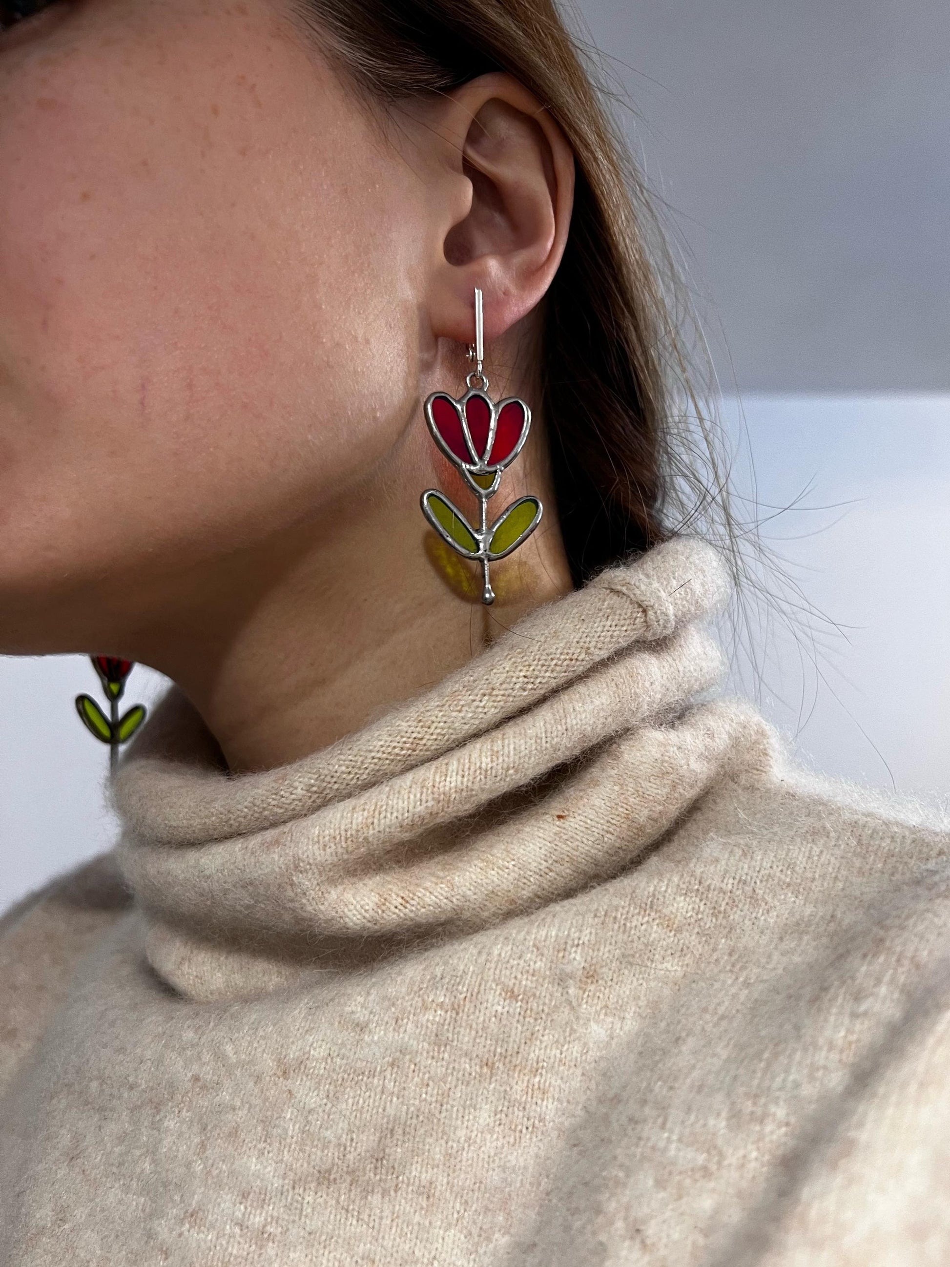 Red stained glass flower earrings worn on ear, botanical dangle jewelry