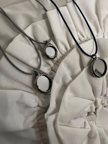 Three stained glass mirror necklaces on fabric