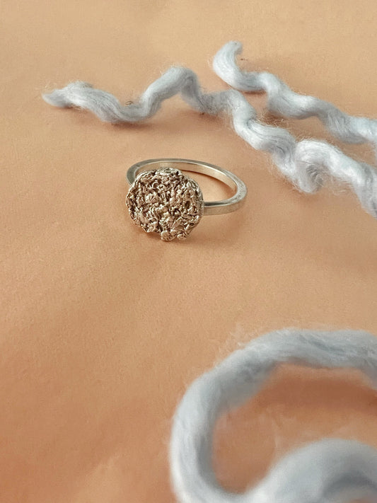 Textured sterling silver disk ring on neutral background