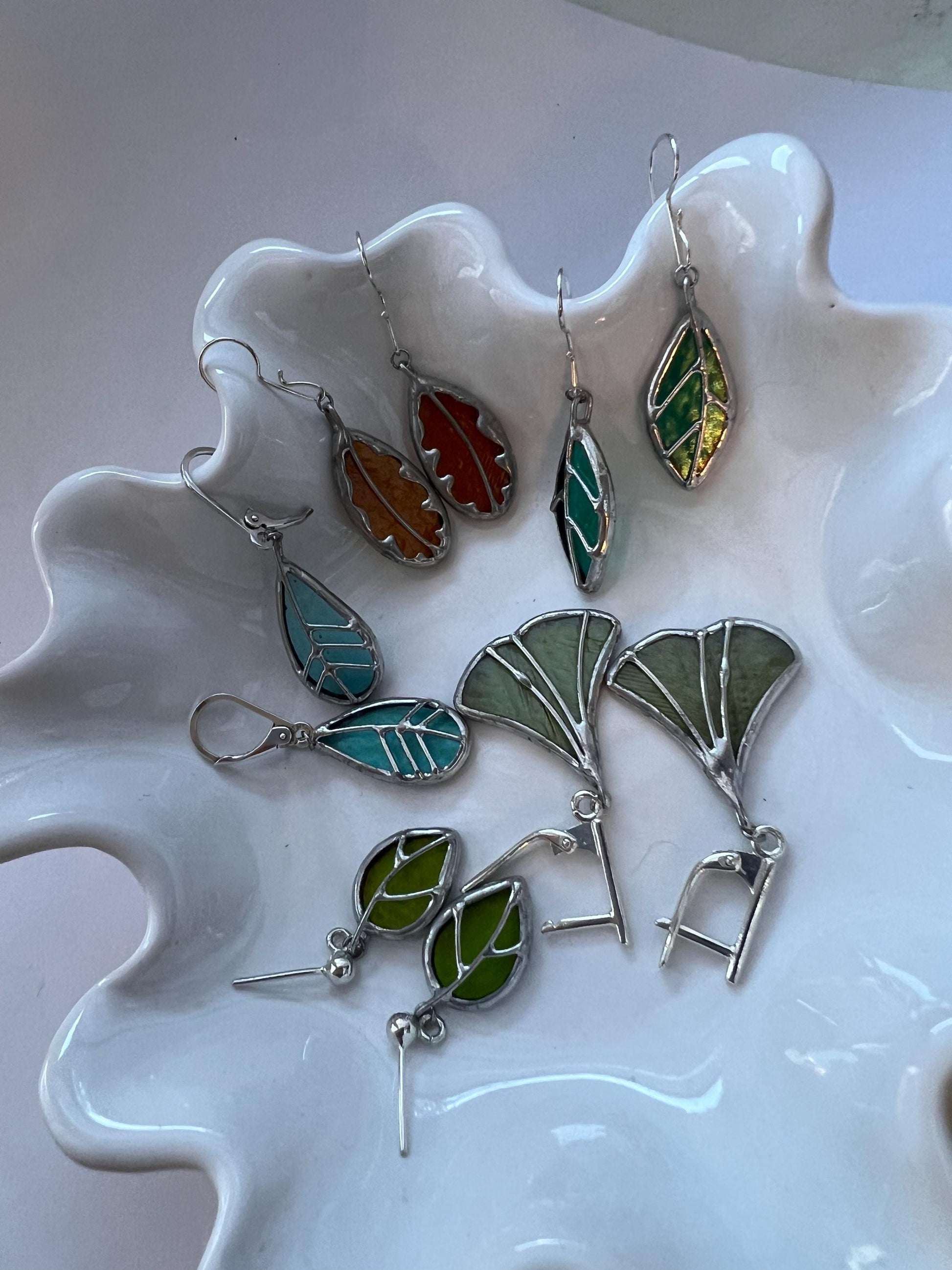 Handmade nature leaf earrings laid out showing size variations