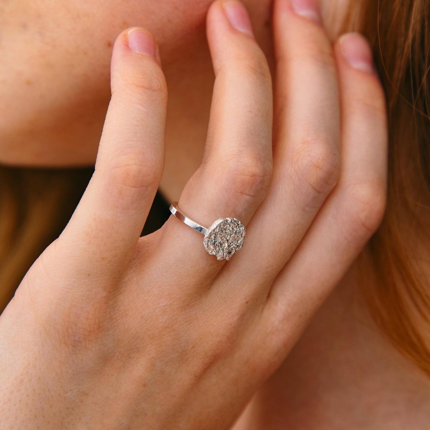 Woman wearing textured silver disk ring – elegant engagement style hand pose
