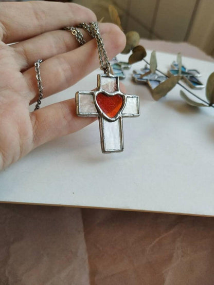 Hand holding chunky cross pendant with red heart detail