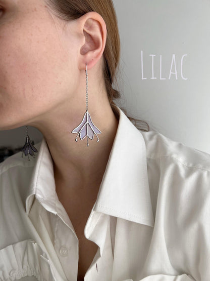 Close-up of handmade purple floral earrings in stained glass with silver chain.