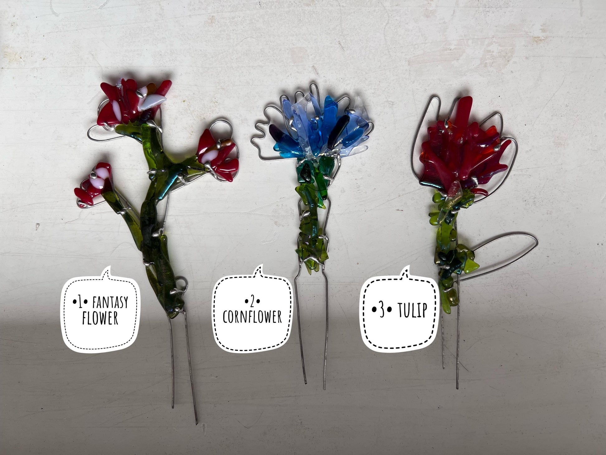 Three fused glass flower stakes in red and blue designs displayed together
