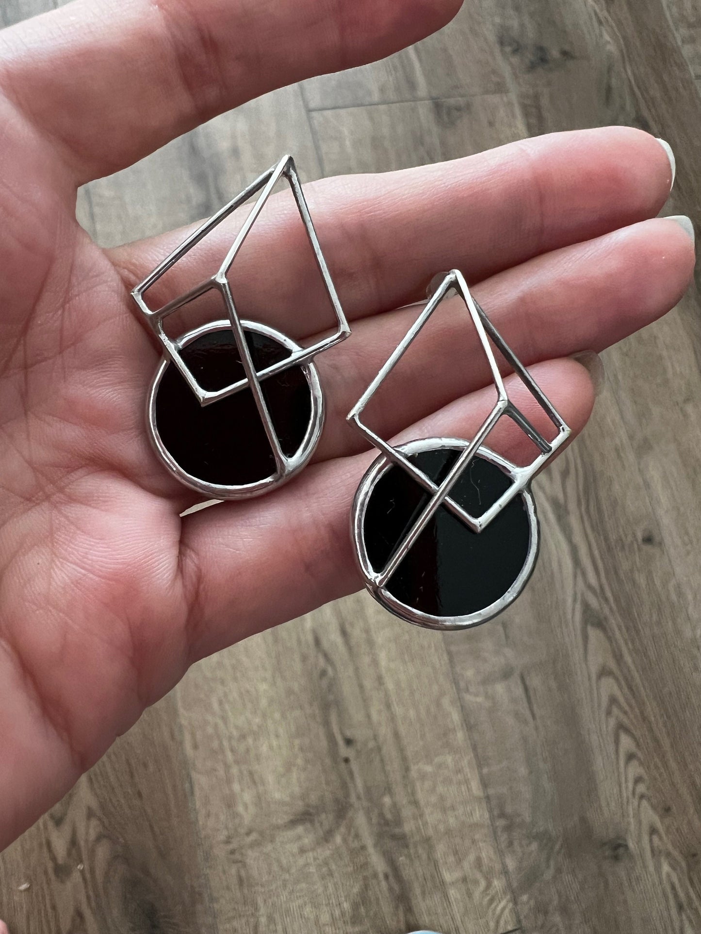 Handmade black geometric stained glass earrings on hand