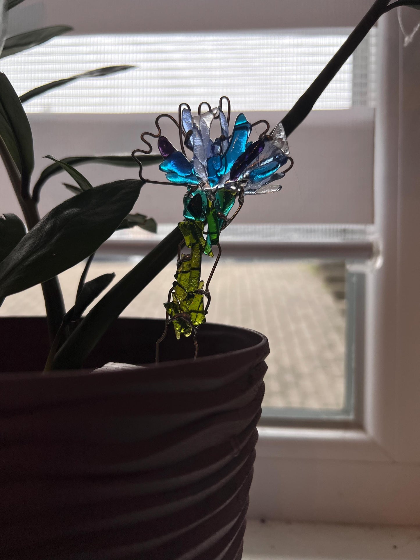 Blue fused glass cornflower plant stake catching sunlight