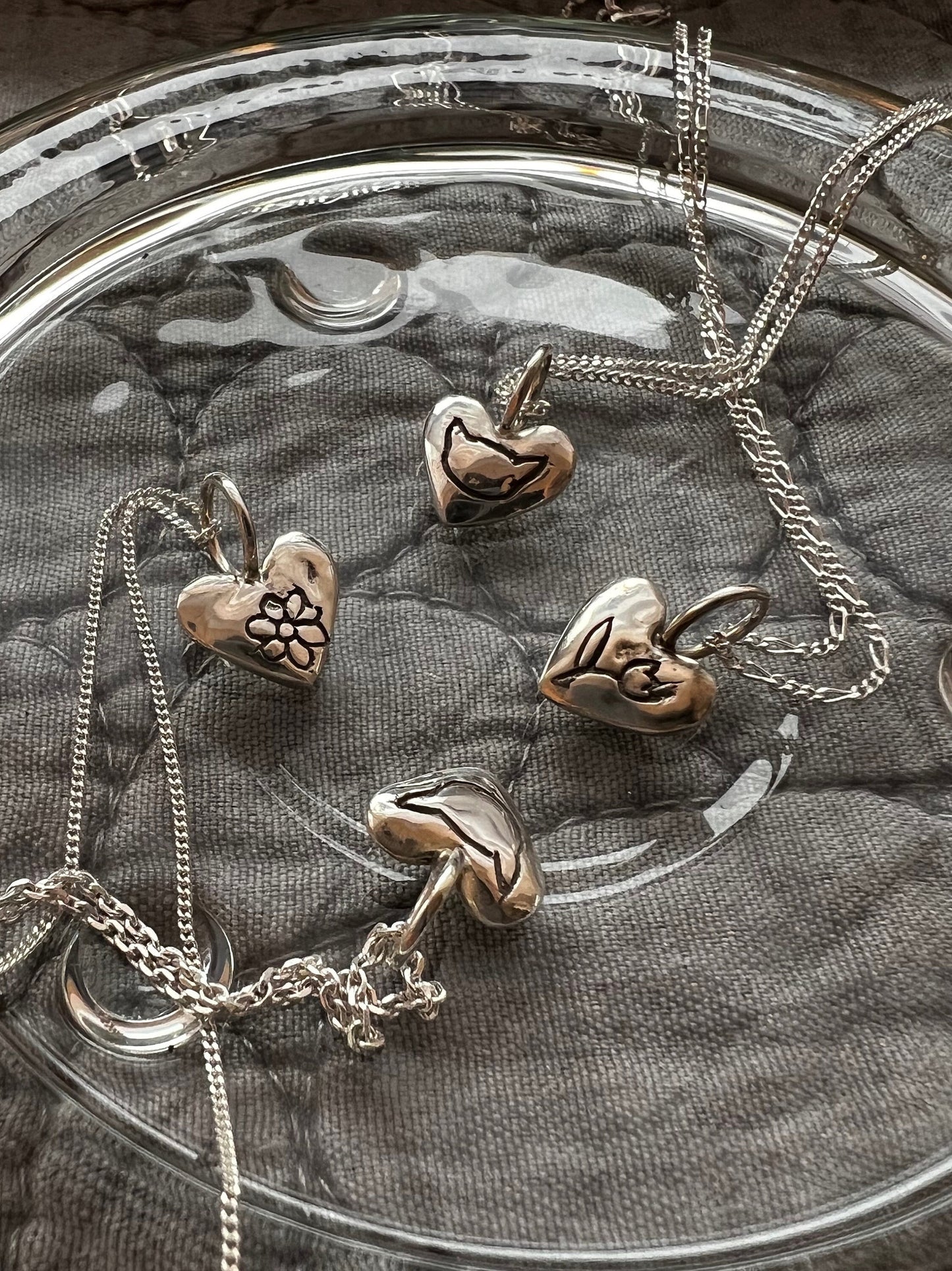 Personalized sterling silver puffy heart necklace on fabric background