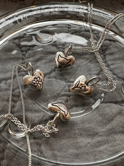 Personalized sterling silver puffy heart necklace on fabric background
