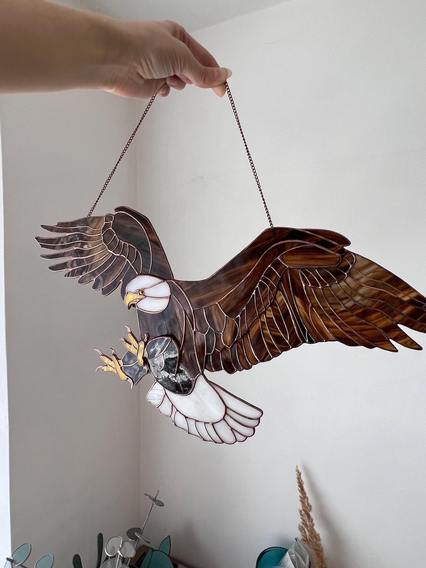 Handmade bald eagle glass suncatcher hanging in window with wings spread
