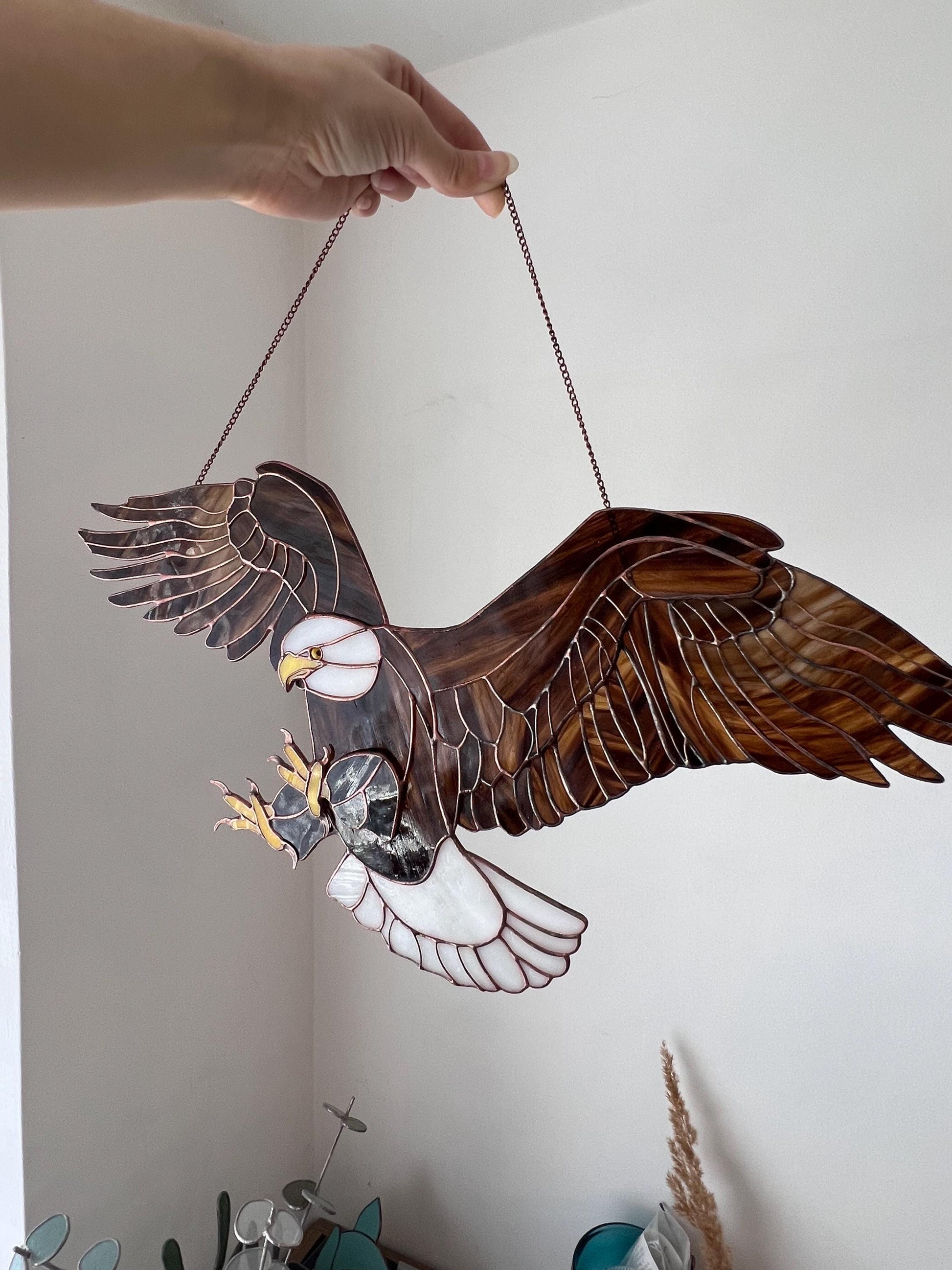 Handmade bald eagle glass suncatcher hanging in window with wings spread