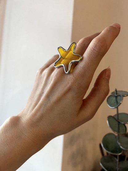 Handmade stained glass ring shaped like a starfish. Ocean-inspired statement jewelry in orange tones.