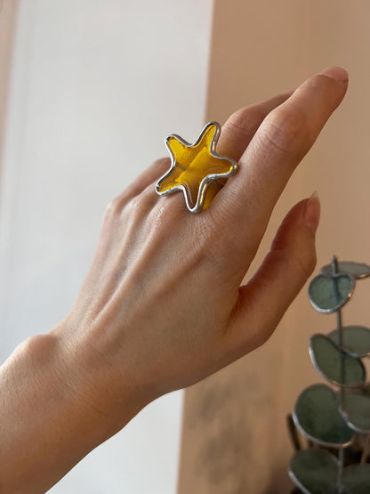 Hand wearing yellow stained glass star ring – handmade statement jewelry.