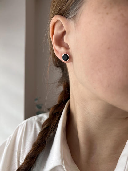 Minimalist round stud earring made of black fused glass with subtle sparkle, mounted on a silver post. Small and modern, perfect for everyday wear.