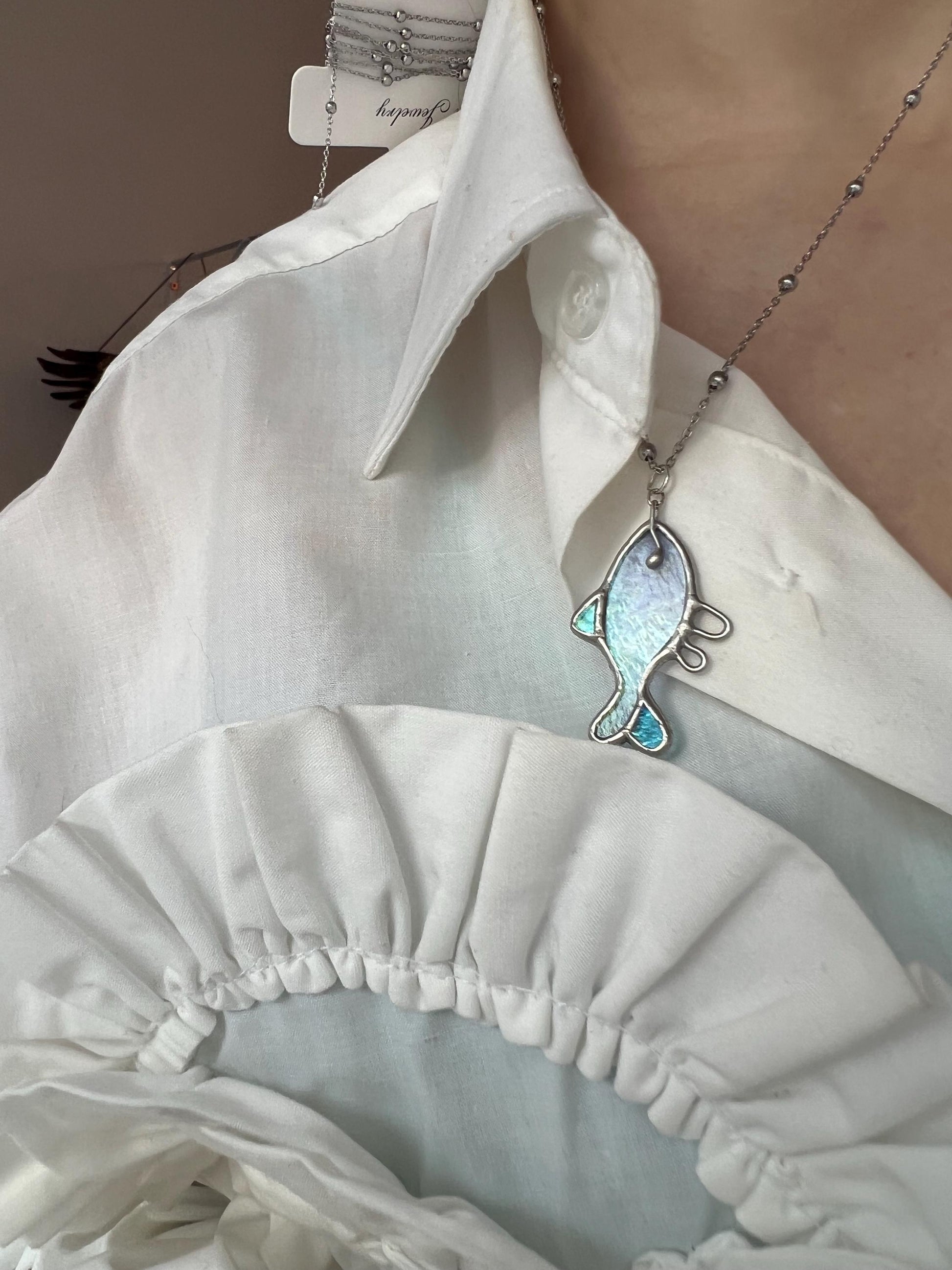 Pastel opal stained glass pendant shaped like an angel fish. Handmade necklace with soft pink and blue hues, reflecting light.