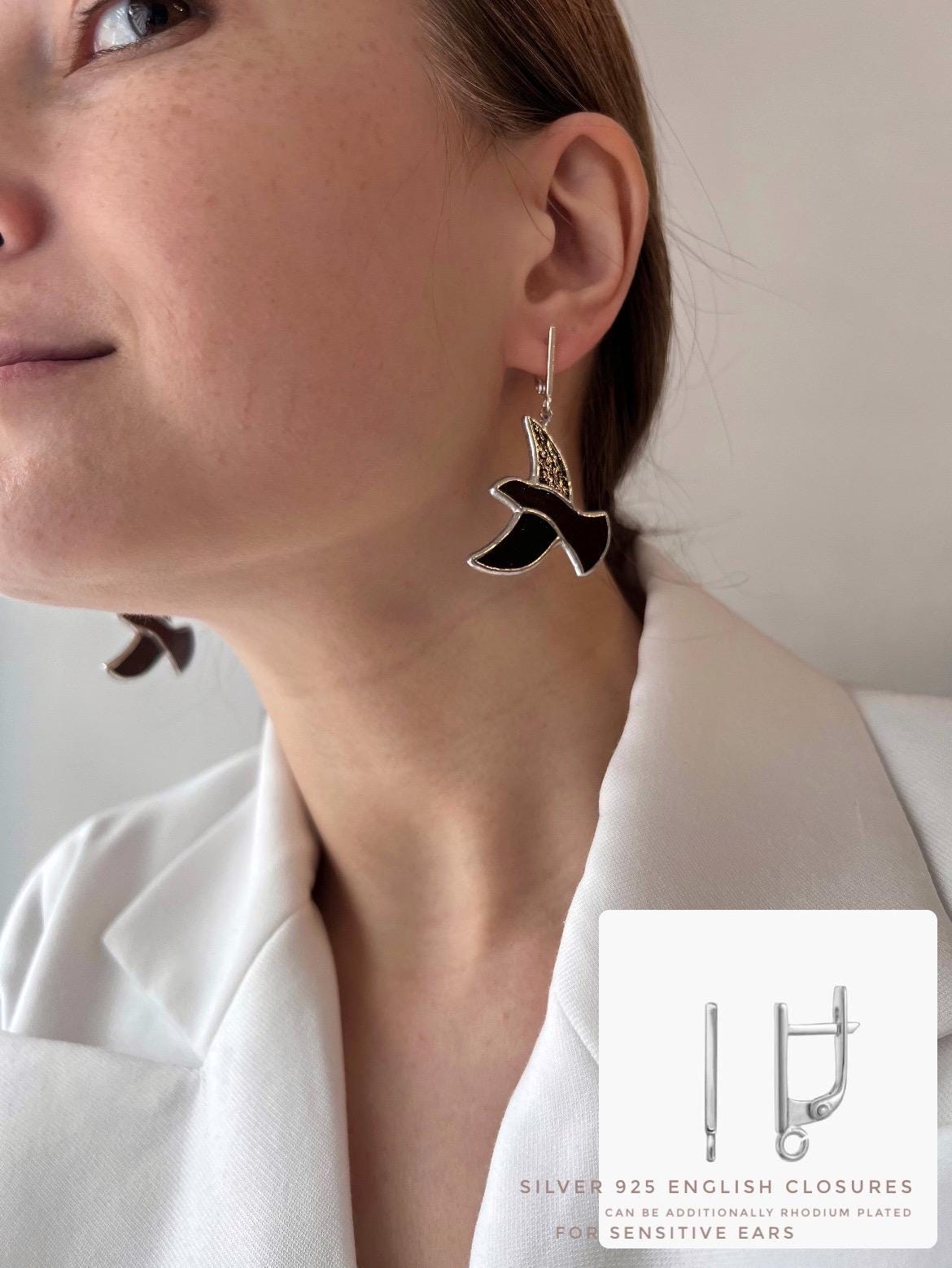 Close-up of a woman wearing handmade stained glass earrings in the shape of a brown bird – lightweight dangle earrings inspired by nature.