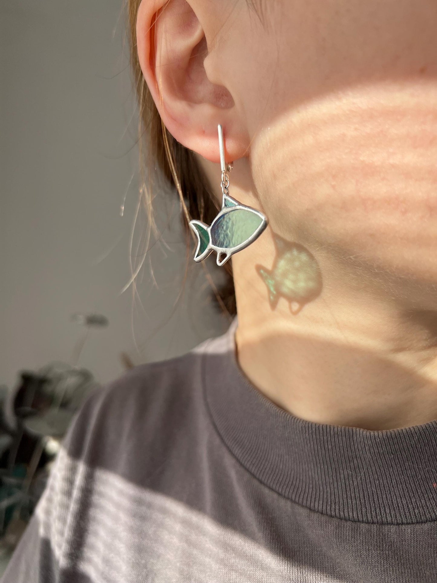 Baby whale stained glass earrings close up, iridescent green glass