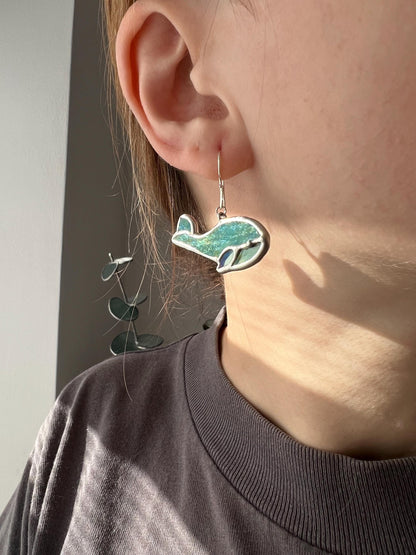 Green stained glass earrings shaped like baby whales. Lightweight handmade ocean-themed dangle earrings.